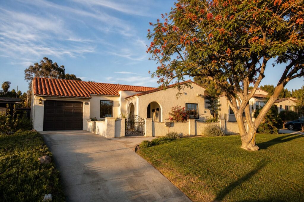Single-story Spanish Colonial home with terra-cotta roof and mature coral tree in a residential College Area neighborhood south of El Cajon Boulevard